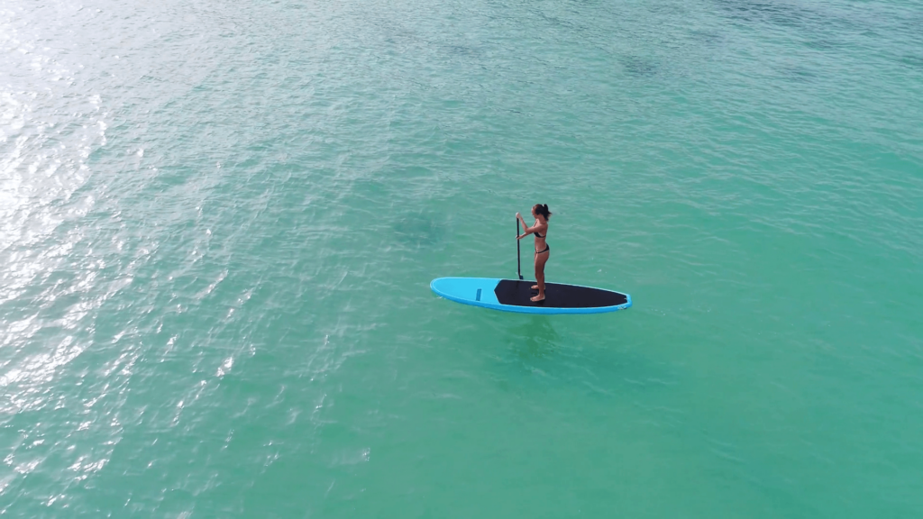 Aerial drone bird’s eye view of man exercising sup paddle board in