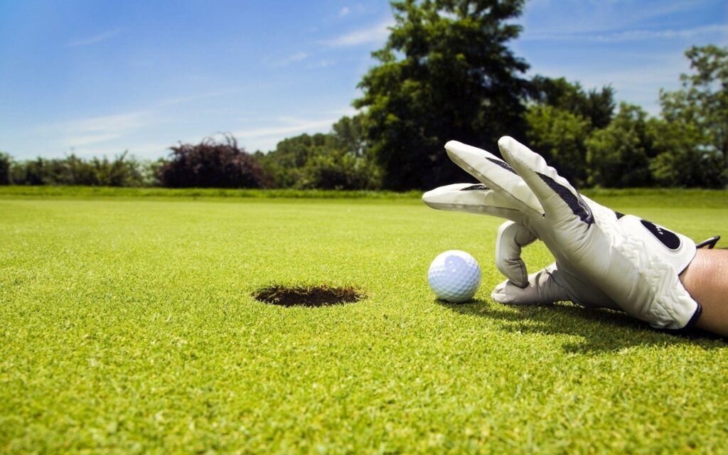 Hand glove push golf ball into hole field wide 2K wallpapers
