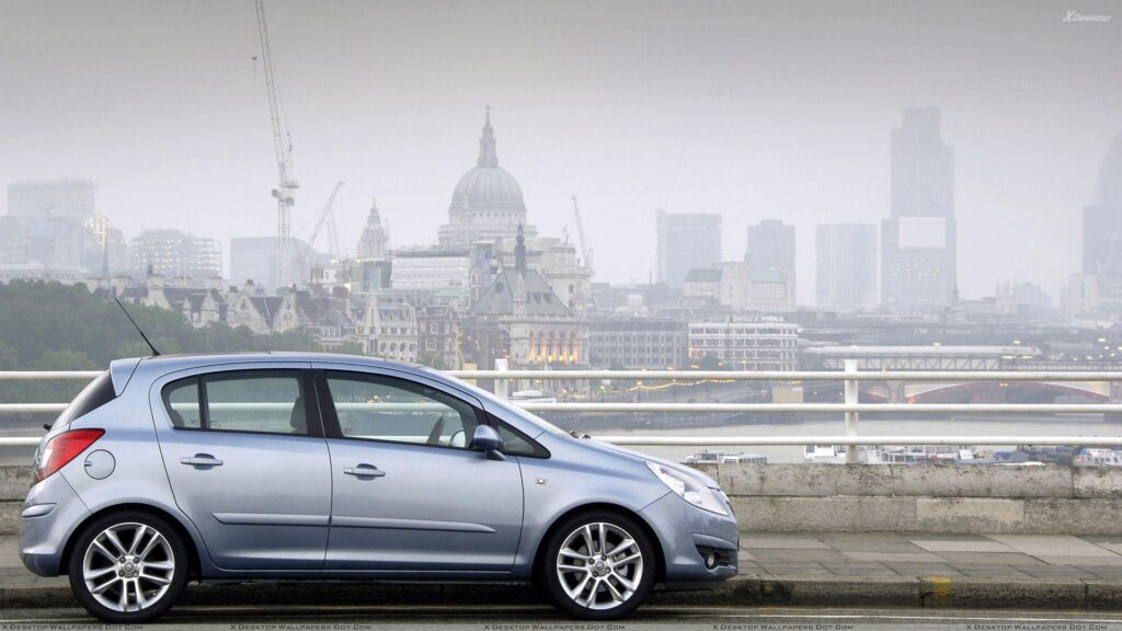 Vauxhall Corsa Side Pose In Blue Near Buildings Wallpapers