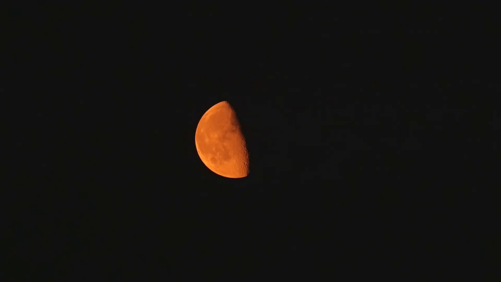 Orange waning gibbous moon against a black night sky Stock Video